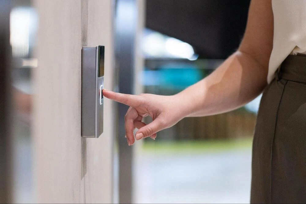 Biometric Access Control System for Offices A person pressing their finger on a biometric access control panel to unlock a door.