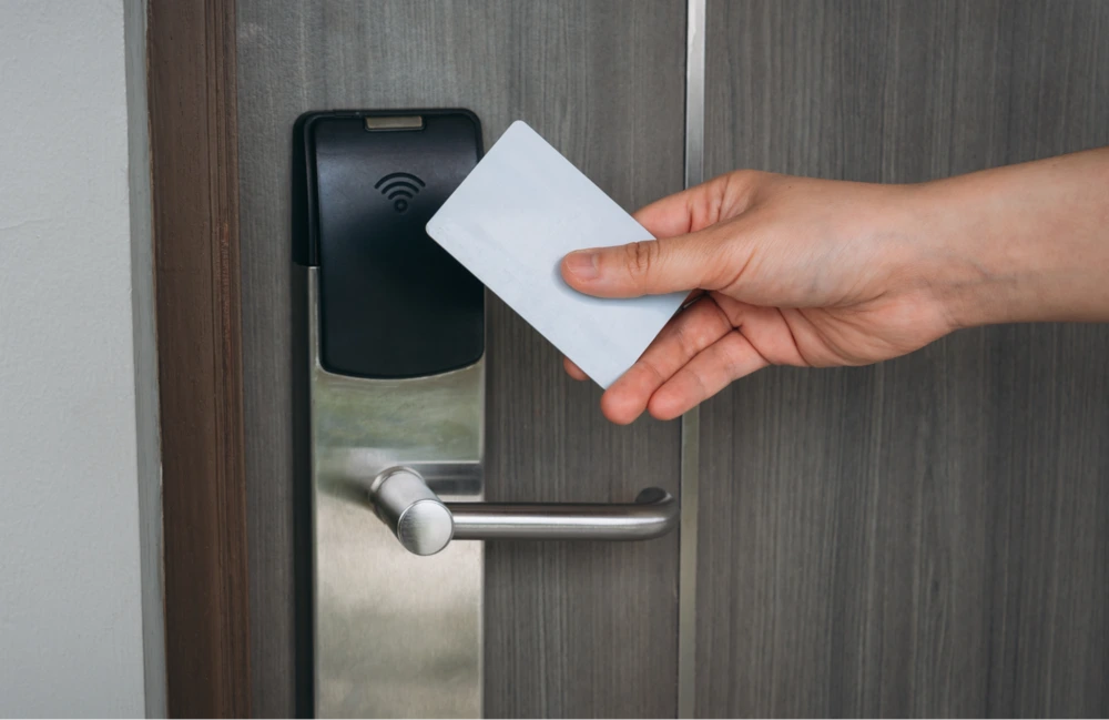 Card-Based Access Control System A hand holding a blank white keycard up to an electronic door lock to demonstrate a card-based access control system.