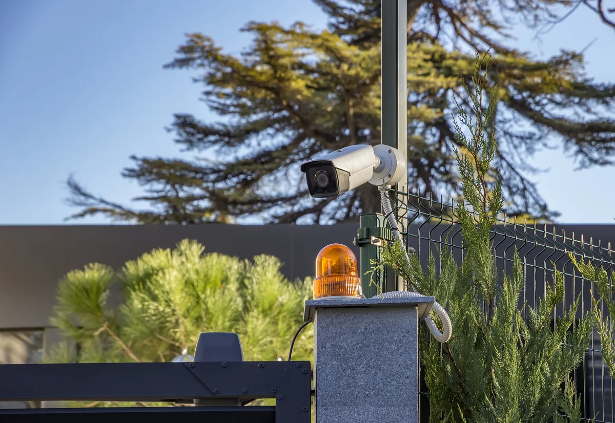 A professional CCTV security camera mounted on a fence for integrated property protection