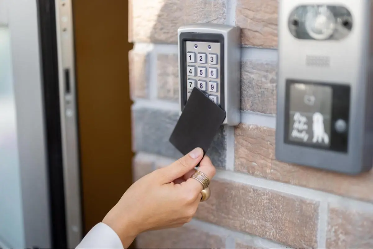 Keycard Proximity Access Control Door System Hand holding a proximity card near a door keypad with an intercom panel for building access control